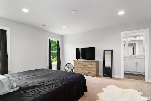 bedroom with light colored carpet, recessed lighting, and ensuite bathroom