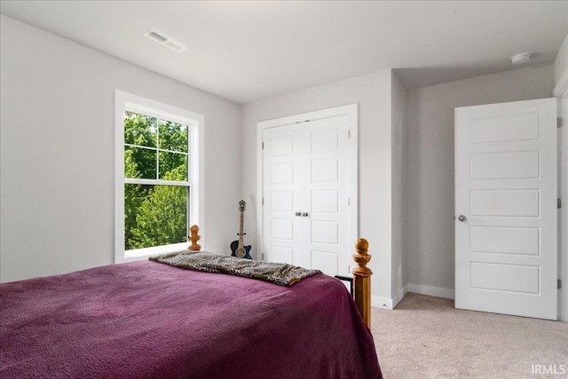 bedroom featuring light colored carpet, baseboards, and a closet