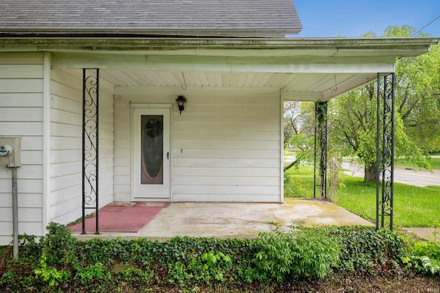 entrance to property featuring a shingled roof and covered porch