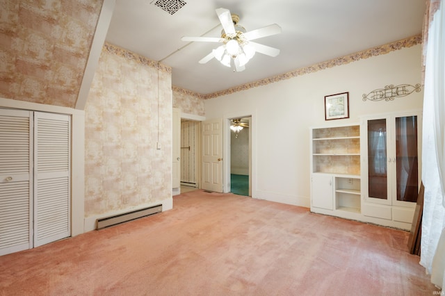 unfurnished bedroom with a baseboard radiator, carpet flooring, a closet, baseboards, and a ceiling fan