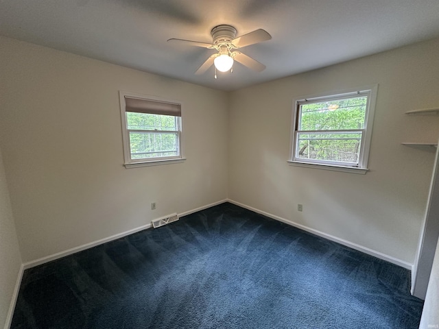 empty room with plenty of natural light, dark carpet, a ceiling fan, and baseboards