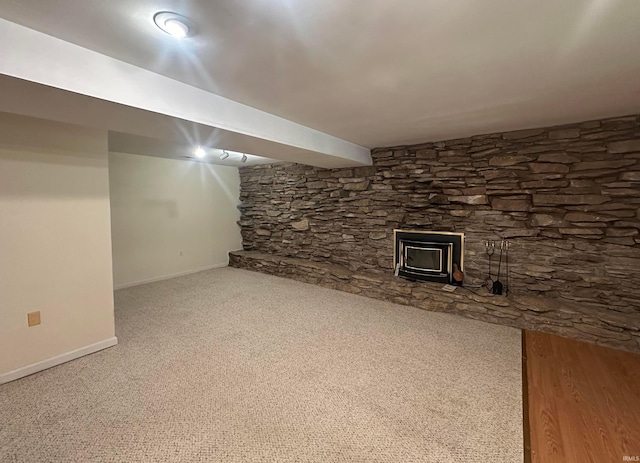 finished below grade area with baseboards, a wood stove, and carpet floors