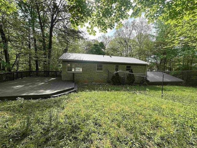 back of property featuring a deck, metal roof, a chimney, and a yard