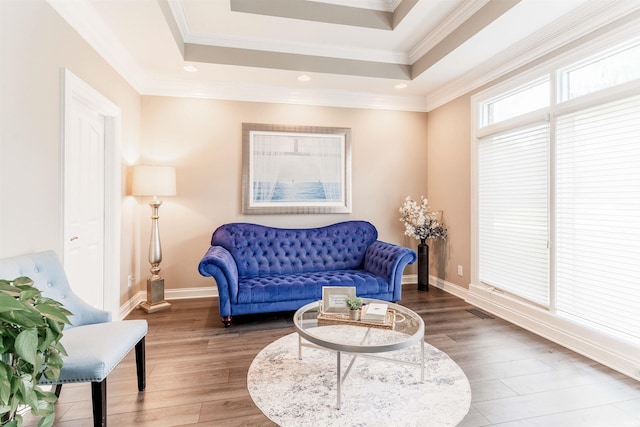 living area featuring wood finished floors, a raised ceiling, baseboards, ornamental molding, and recessed lighting