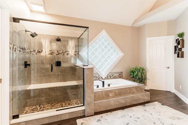 bathroom featuring wood finished floors, a shower stall, a bath, vaulted ceiling, and baseboards