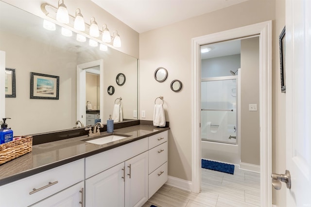 bathroom with vanity, shower / bath combination with glass door, and baseboards