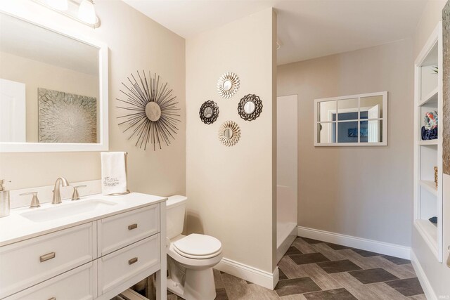 bathroom featuring toilet, vanity, and baseboards