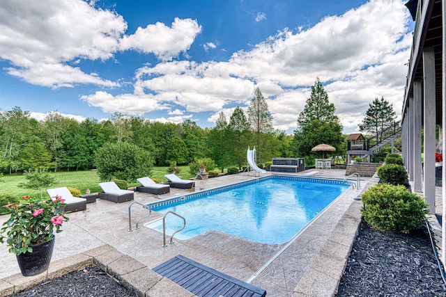 outdoor pool featuring a water slide and a patio