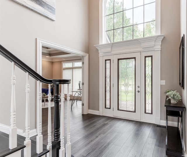 foyer with a towering ceiling, dark wood-type flooring, stairs, baseboards, and ornamental molding