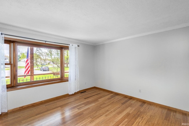 unfurnished room with light wood-type flooring, baseboards, crown molding, and a textured ceiling
