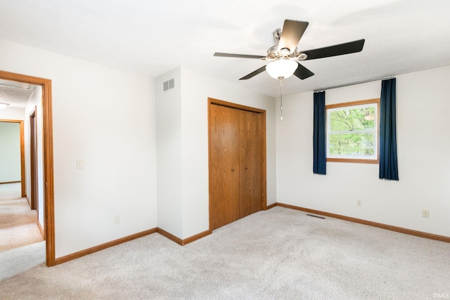 unfurnished bedroom with light colored carpet, a closet, ceiling fan, and baseboards