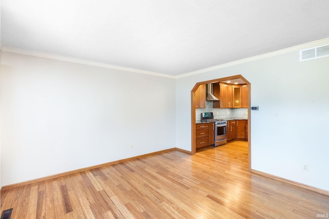 unfurnished living room featuring light wood-type flooring, baseboards, crown molding, and arched walkways