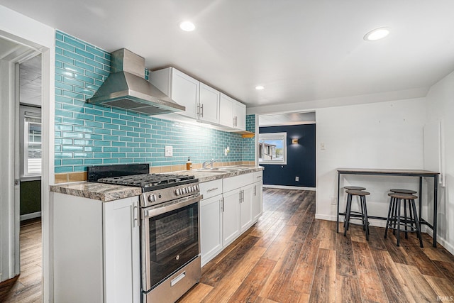 kitchen with gas range, wall chimney range hood, baseboards, wood finished floors, and recessed lighting