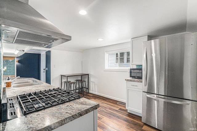 kitchen featuring freestanding refrigerator, ventilation hood, a sink, dark wood-style flooring, and white cabinets