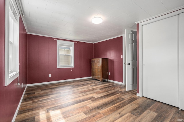 unfurnished bedroom featuring wood finished floors, ornamental molding, a closet, and baseboards