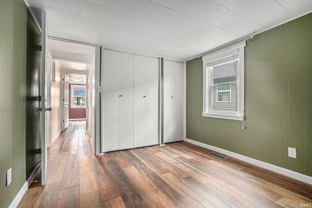 unfurnished bedroom featuring wood-type flooring, a closet, and baseboards