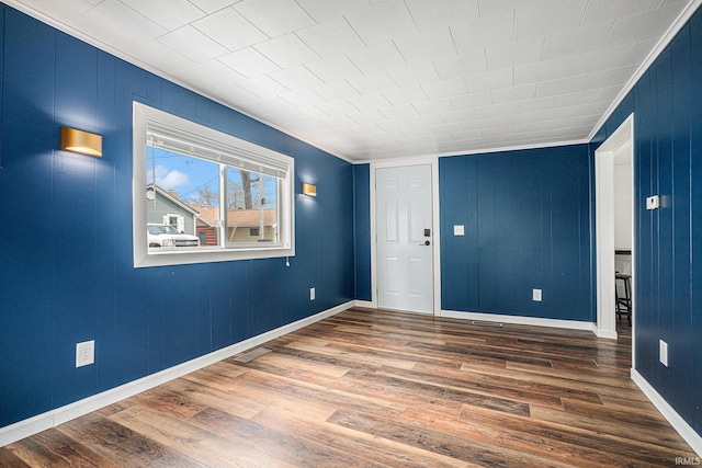 unfurnished room featuring crown molding, wood finished floors, and baseboards