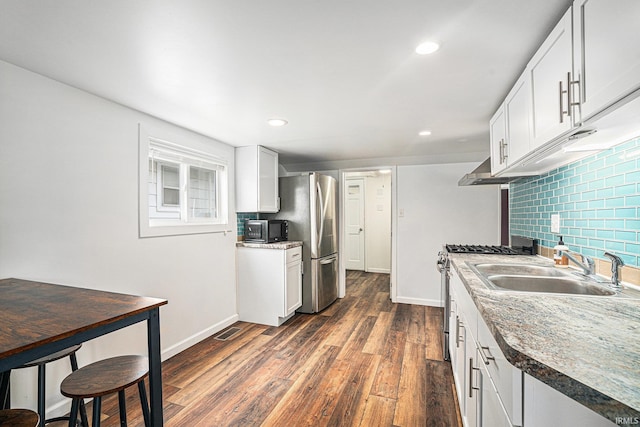 kitchen featuring stainless steel appliances, a sink, baseboards, dark wood-style flooring, and recessed lighting
