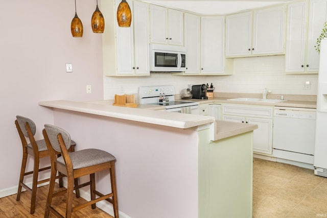 1005 E Buckingham Dr, Bloomington, IN 47401 - kitchen featuring white appliances, a sink, a breakfast bar, and tasteful backsplash