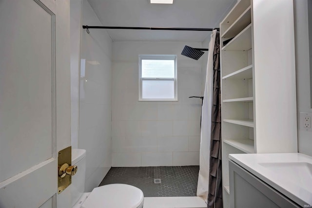 bathroom with toilet, tiled shower, and vanity