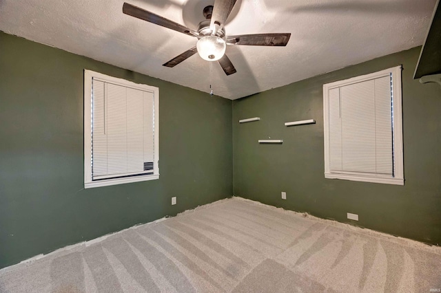 carpeted empty room featuring ceiling fan, a textured ceiling, and baseboards