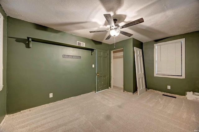 unfurnished bedroom with carpet, a textured ceiling, a ceiling fan, and a closet