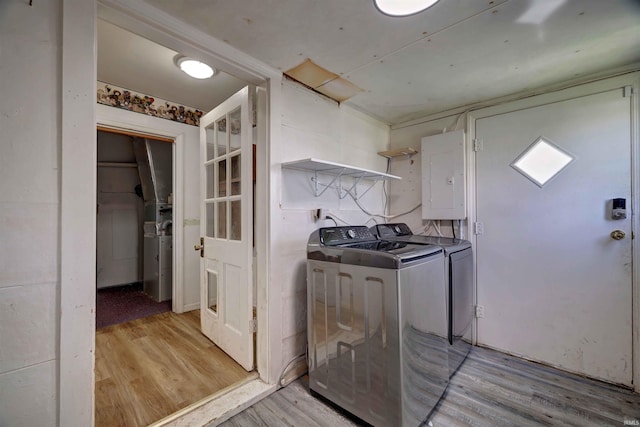 laundry room featuring washing machine and dryer, electric panel, and light wood-style floors