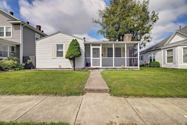 view of front of property with a sunroom, a front lawn, and a chimney