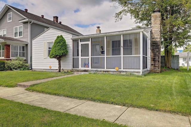 view of front of property with a chimney, a sunroom, and a front yard