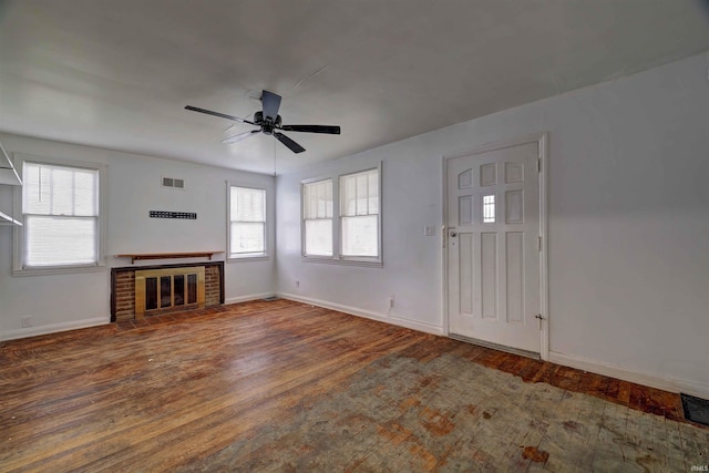 unfurnished living room with wood finished floors, baseboards, a ceiling fan, and a brick fireplace