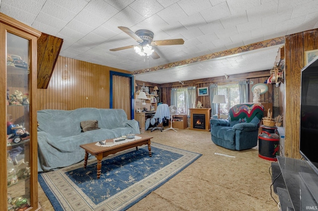 7950 E Metz Rd, Angola, IN 46703 - living room featuring carpet, wooden walls, ceiling fan, and a lit fireplace