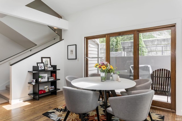 dining room featuring stairs, wood finished floors, and lofted ceiling