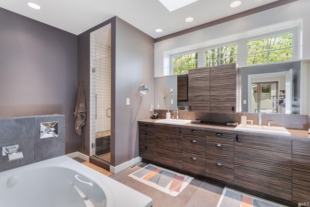 full bath featuring a garden tub, a shower stall, double vanity, recessed lighting, and a skylight
