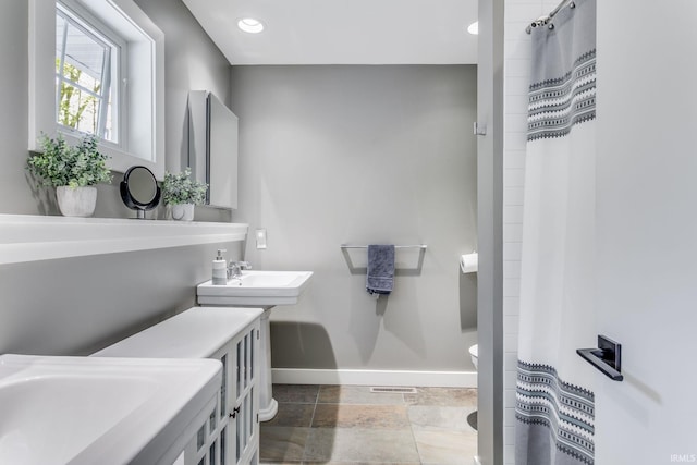 full bathroom with baseboards, recessed lighting, curtained shower, toilet, and stone finish floors
