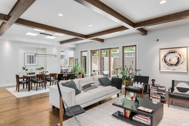 living area with coffered ceiling, beam ceiling, light wood-type flooring, a skylight, and baseboards
