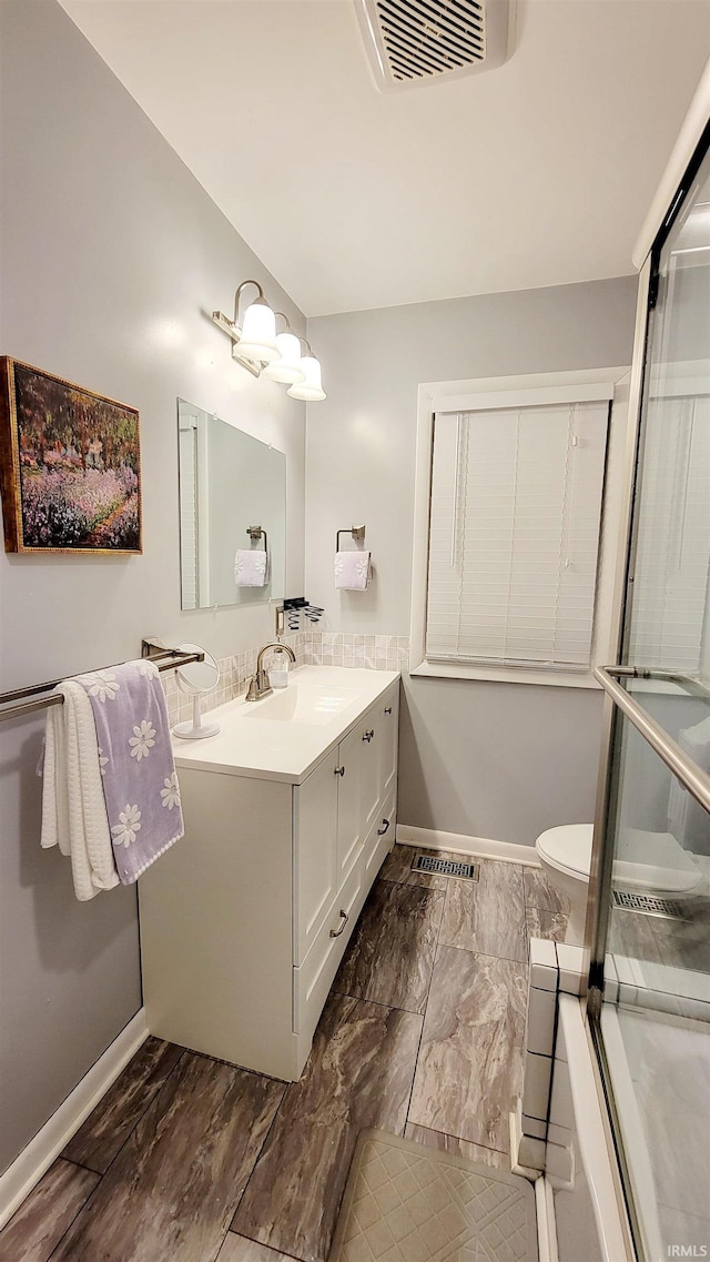 bathroom with baseboards, vanity, toilet, and marble look tile flooring