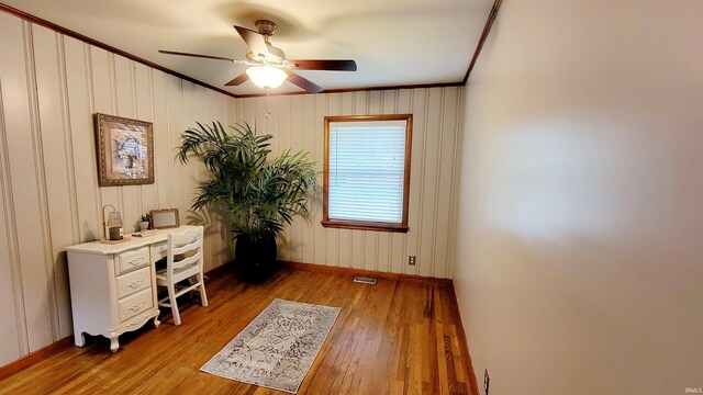 home office featuring ornamental molding, baseboards, light wood finished floors, and a ceiling fan