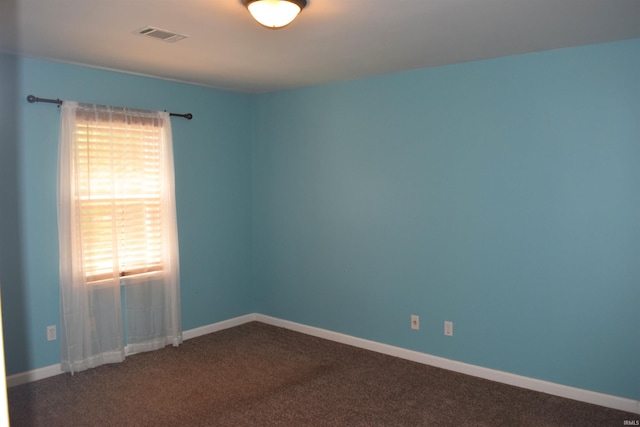 spare room with dark colored carpet and baseboards