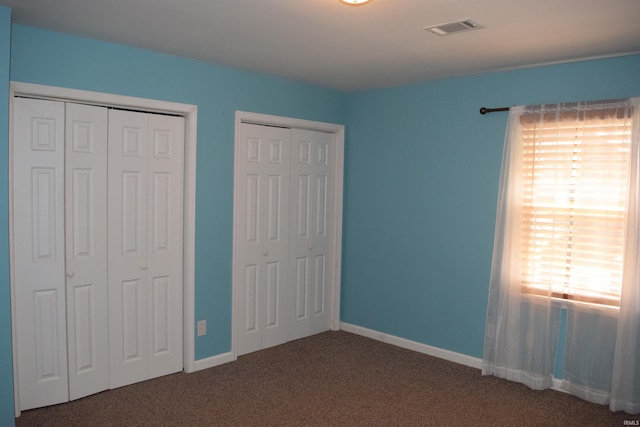 unfurnished bedroom with carpet, multiple closets, and baseboards