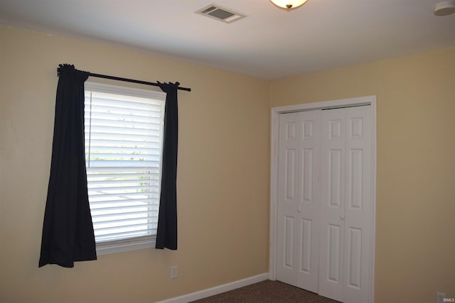 unfurnished bedroom with carpet, a closet, and baseboards