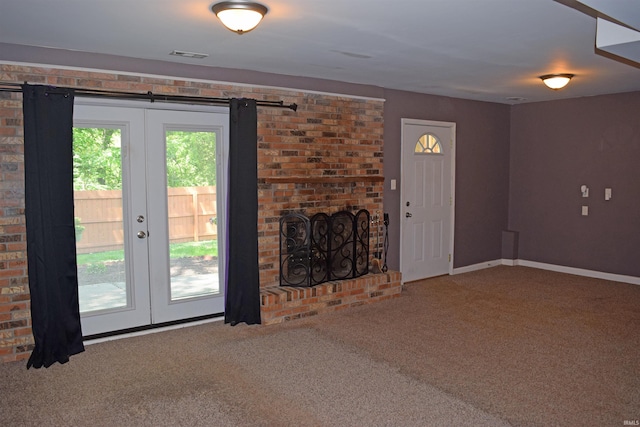 unfurnished living room featuring carpet flooring, a fireplace, baseboards, and french doors