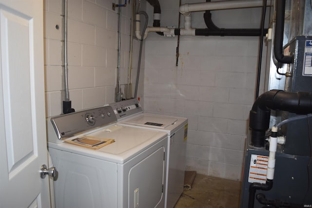washroom with washing machine and dryer, concrete block wall, and heating unit