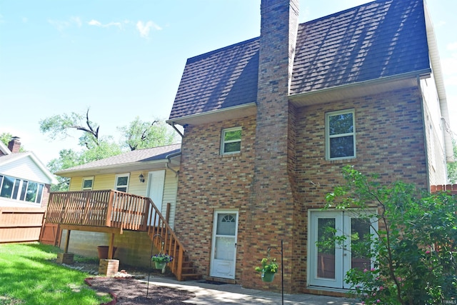 rear view of house with a chimney, brick siding, french doors, a wooden deck, and stairs