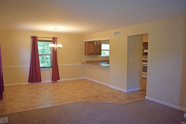 kitchen with a chandelier, white range oven, pendant lighting, a sink, and light tile patterned floors