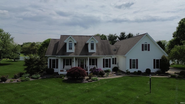 cape cod house with covered porch, a front lawn, and a shingled roof