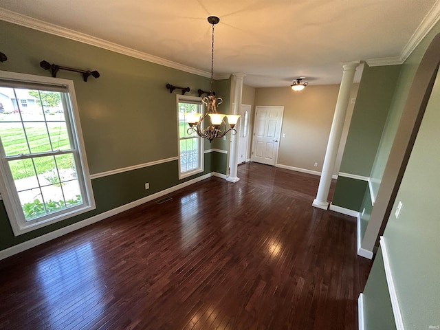 unfurnished dining area with dark wood-type flooring, baseboards, crown molding, ornate columns, and a chandelier