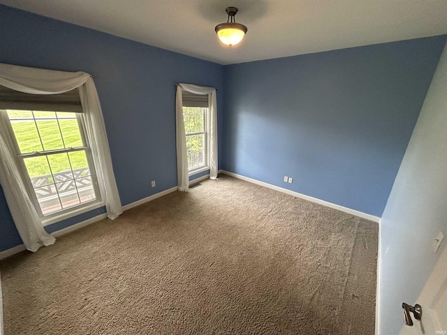 unfurnished room featuring plenty of natural light, carpet floors, and baseboards