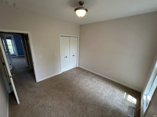 unfurnished bedroom with carpet flooring, baseboards, and a closet