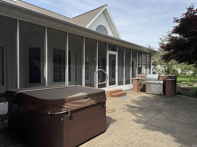 view of patio / terrace featuring a hot tub, a sunroom, and entry steps