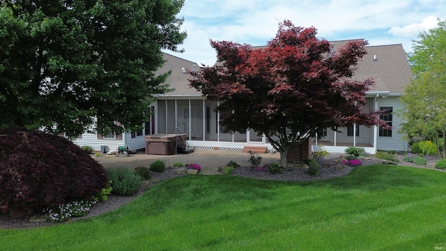 view of front of property with a sunroom, a patio area, a front lawn, and a shingled roof
